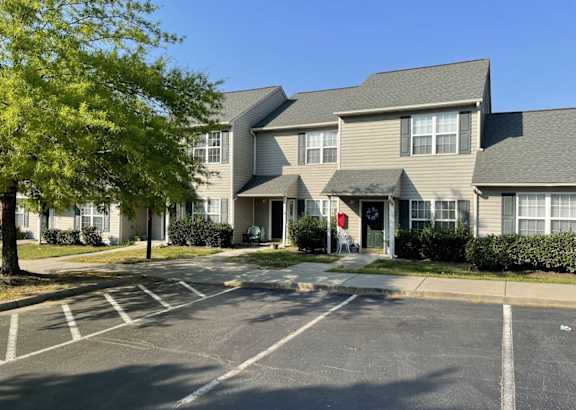 A parking lot in front of a building with a red door.