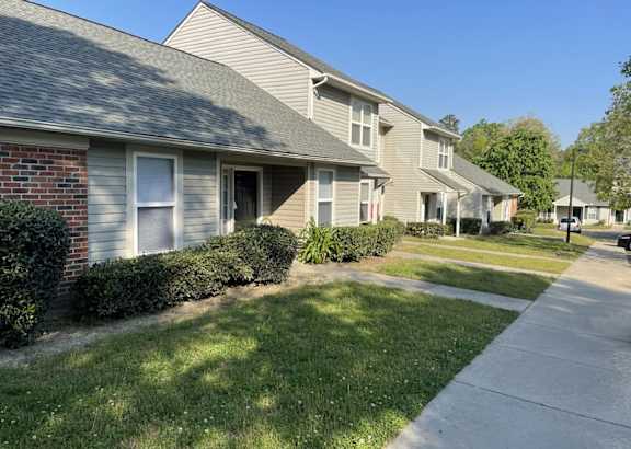 A row of houses with a sidewalk in front.