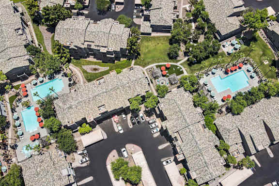 A bird's eye view of a residential area with houses, roads, and a swimming pool.