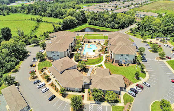 Aerial view of property showing outdoor entertaining areas including pool, gas grills, fire pit, cornhole and fountain