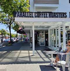 a woman sitting at a table in front of a coffee shop