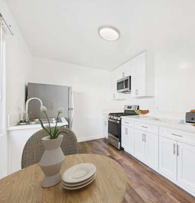 A kitchen with white cabinets and a wooden table.