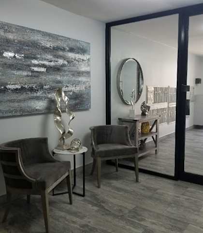 a living room with a large painting on the wall and two chairs