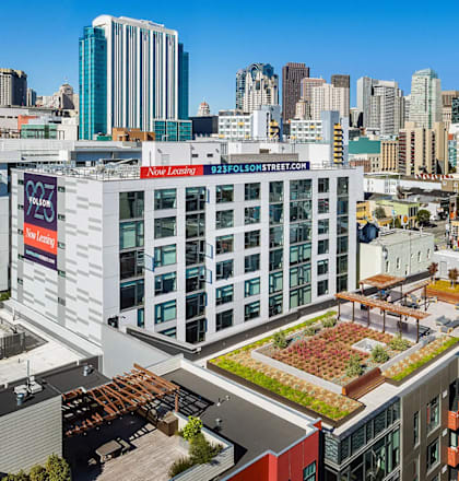 A view of a city with a building that has a green roof and a sign that says "New Luxury".