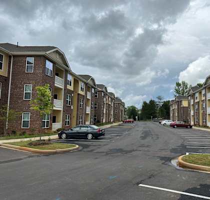 A car is parked on the street in front of apartment buildings.