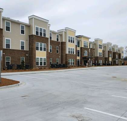 Apartment complex with a parking lot in front.