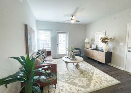 A living room with a couch, a chair, a coffee table, and a potted plant.