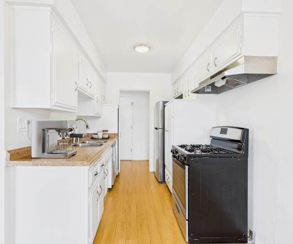 A kitchen with white cabinets and a black stove top oven.
