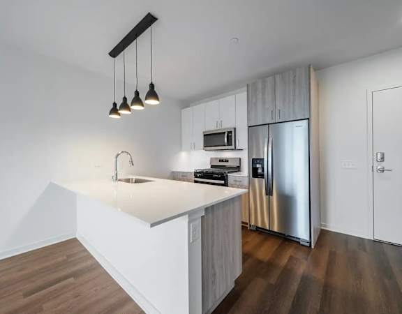 A modern kitchen with a white countertop and stainless steel appliances.