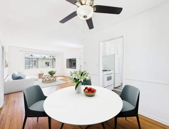 A white dining table with a bowl of fruit on it and two chairs.