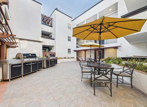 A patio with a table and chairs and an umbrella.