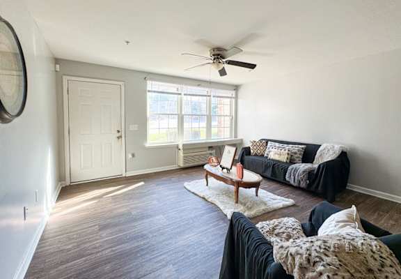 a living room with couches and a coffee table and a ceiling fan