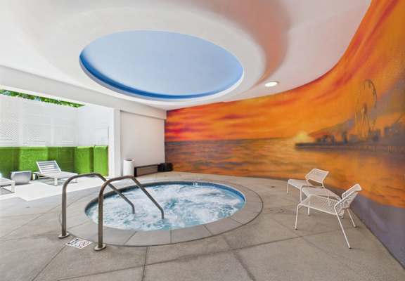 A hot tub in a room with a mural of a sunset.
