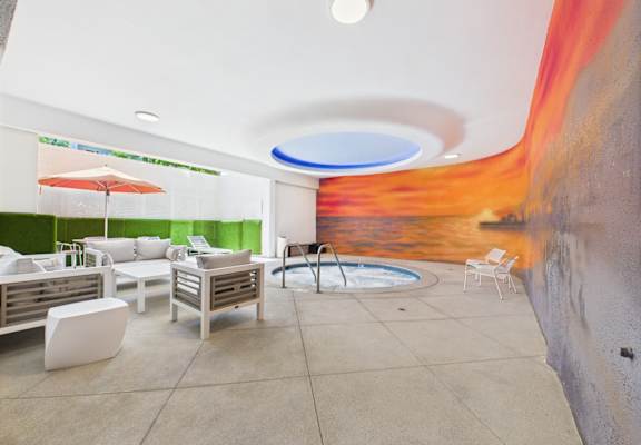 A modern outdoor seating area with a pool and a mural on the wall.