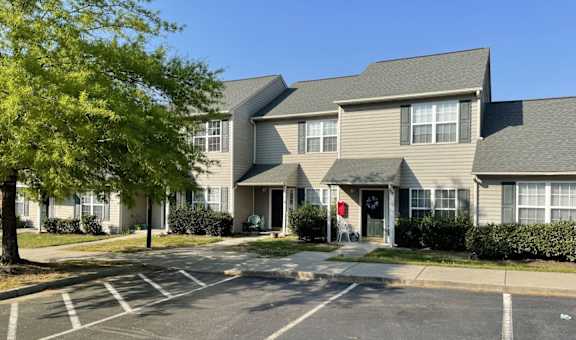 A parking lot in front of a building with a red door.