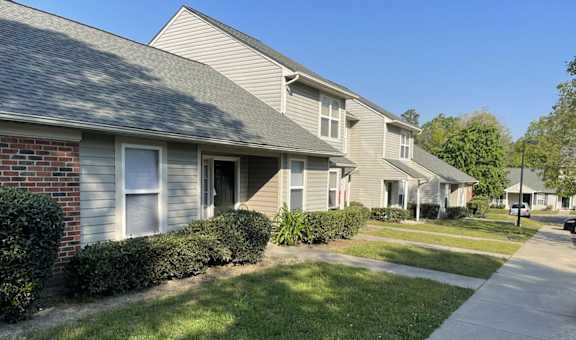 A row of houses with a sidewalk in front.
