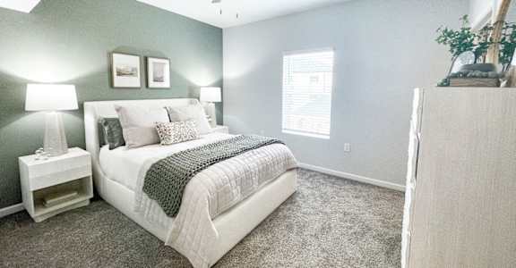 A bedroom with a bed, nightstand, and a ceiling fan.