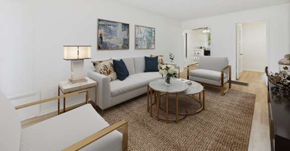 A living room with a white couch, a coffee table, and a painting on the wall.