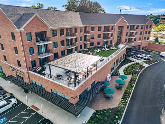 A large red brick hotel with a parking lot in front.