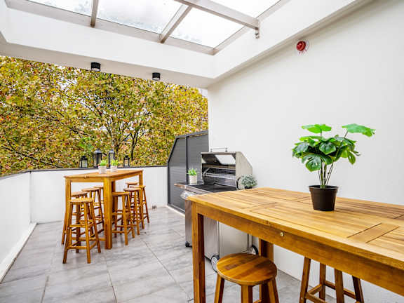 a dining area with a wooden table and chairs and a balcony with a grill