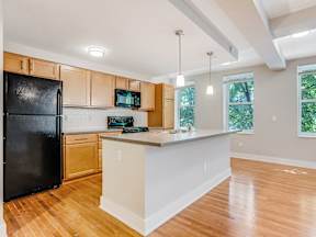 A kitchen with black fridge and wooden cabinets.