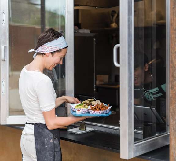 A woman is holding a plate of food at Bautista Apartments, Tucson, AZ