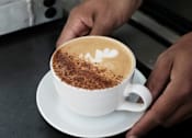 Thumbnail 35 of 46 - A person is holding a cup of coffee at Bautista Apartments, Arizona