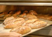 Thumbnail 37 of 46 - A person is taking bread out of an oven at Bautista Apartments, Tucson, AZ, 85745