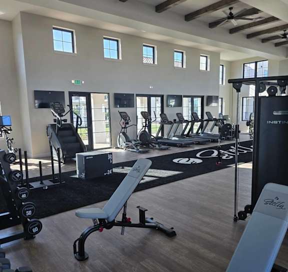 a gym with weights and cardio machines and a large sign on the floor at Stella, San Tan Valley, 85143