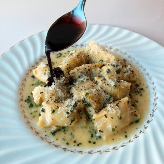 a bowl of pasta with sauce on a white plate at Versus, Calgary, Alberta, T2R 1A8