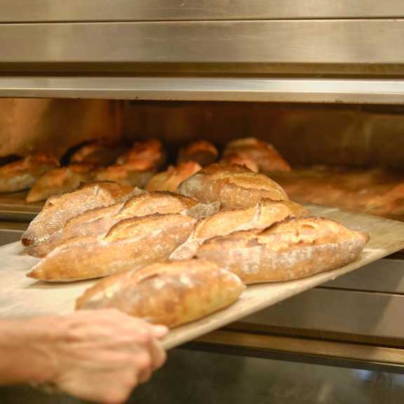 A person is taking bread out of an oven at Bautista Apartments, Tucson, AZ, 85745