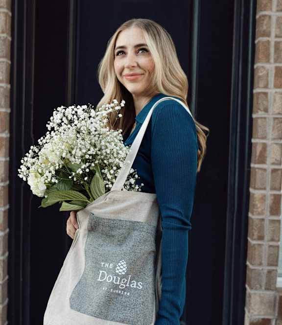 a woman holding a tote bag with flowers