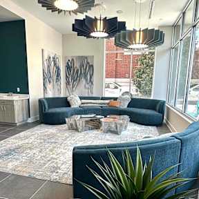 A living room with a blue couch and a rug.