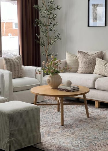 A living room with a white couch, a wooden coffee table, and a striped ottoman at Crogman School Lofts in Atlanta, GA 30315