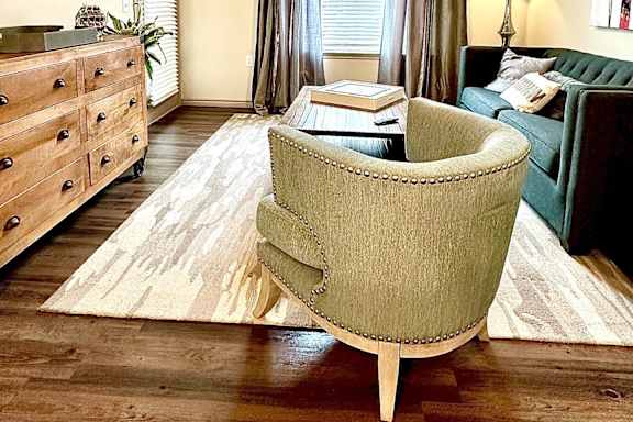 A living room with a green chair and a rug.