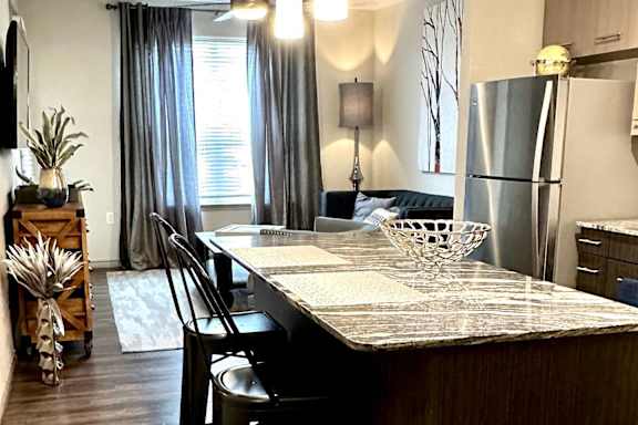 A kitchen with a long island and chairs.