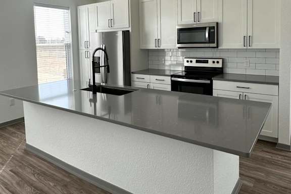 a kitchen with white cabinets and a black counter top