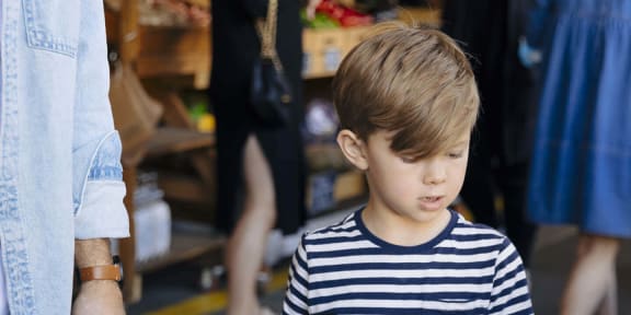 a young boy is looking at a box of vegetables