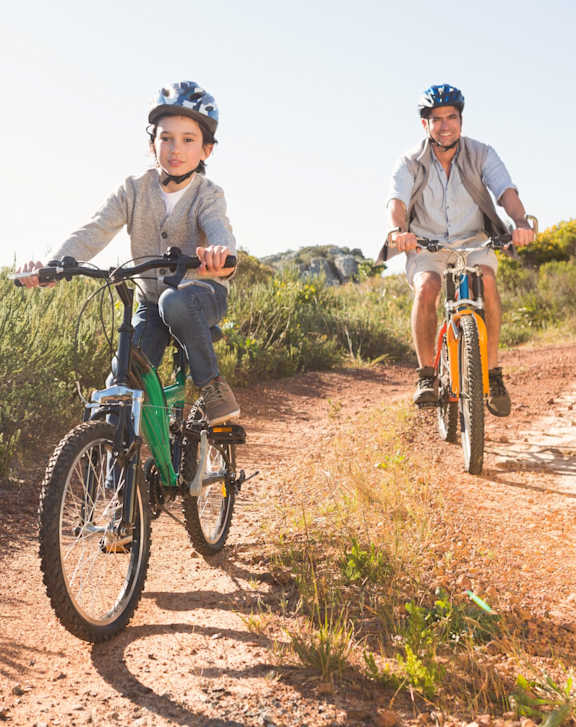 A young boy and an adult are riding bikes on a dirt trail.
