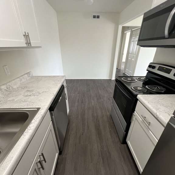 A kitchen with white cabinets and a black stove top oven.