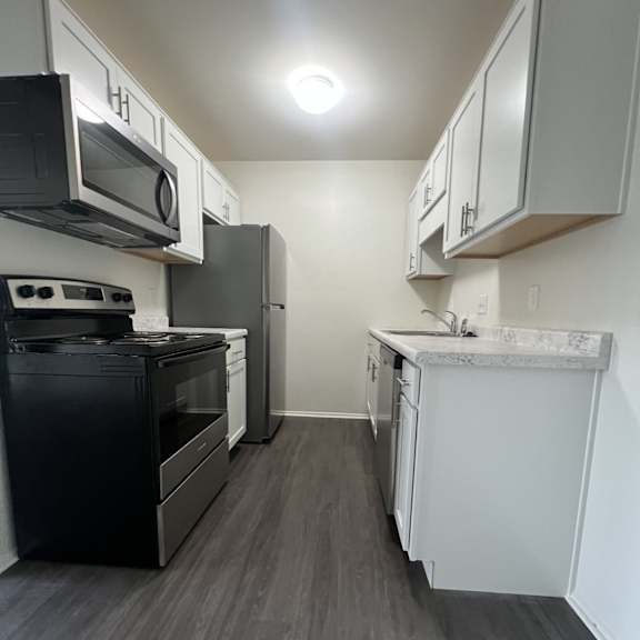A kitchen with black appliances and white cabinets.