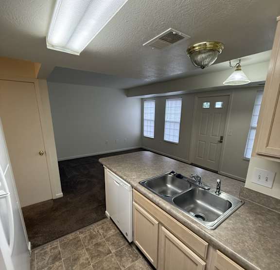 A kitchen with a sink, refrigerator, and cabinets.