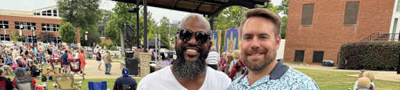Two men standing in front of a crowd at an outdoor event.