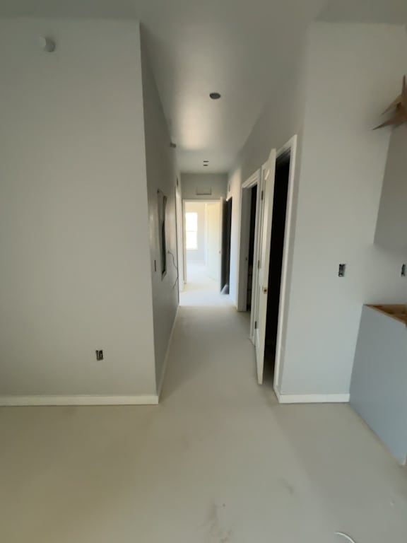 A long, narrow hallway with white walls and a wooden bench on the right.