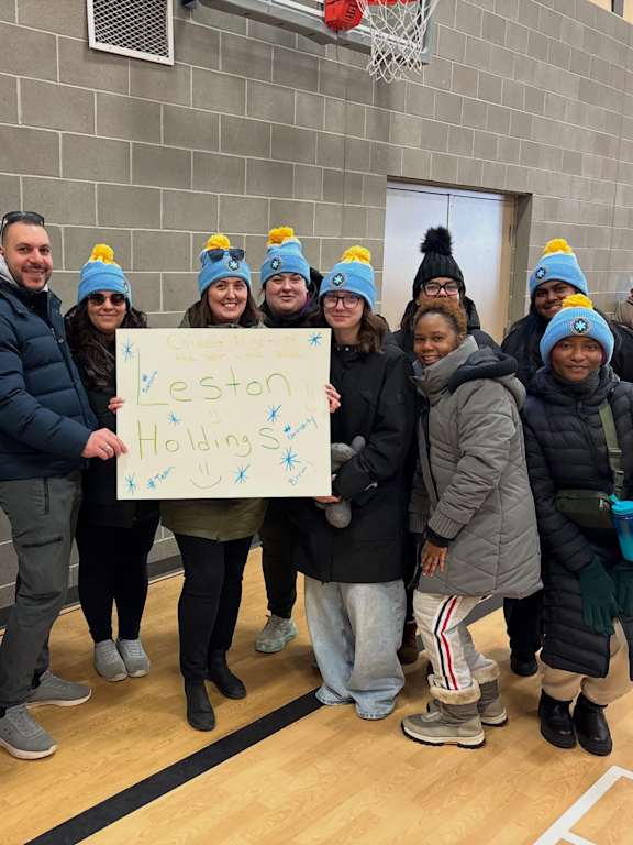 A group of people wearing blue hats holding a sign that says "Leston Holidays".
