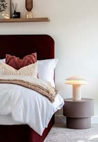 a bedroom with a bed and a nightstand with a lamp and a framed picture