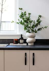 a modern kitchen with grey cabinets and black appliances