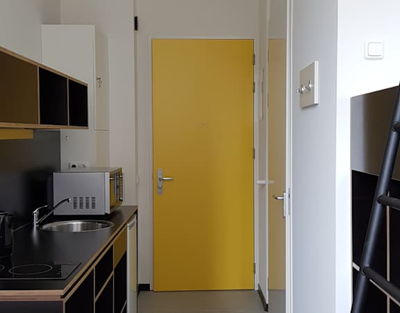 A modern kitchen with a yellow backsplash and black countertops.
