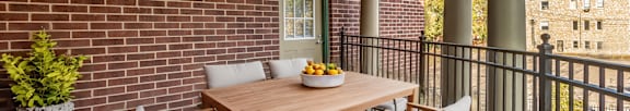 A table with a bowl of fruit on it sits on a balcony.