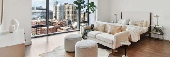 A white bedroom with a large bed and a view of the city.